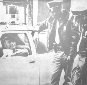 Police officer Charlie Jones standing with another officer talking with a man in a vehicle.