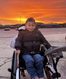 Dianne's daughter in wheelchair sitting in front of a sunset.